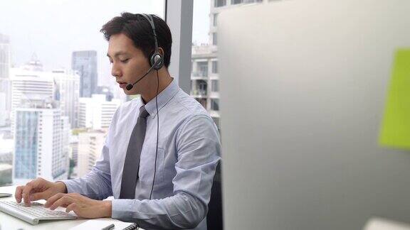 英俊的亚洲电话推销员在办公室工作