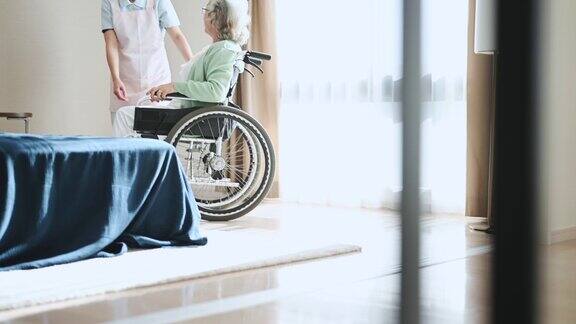 在养老院帮助坐轮椅的老年妇女的年轻女性护工
