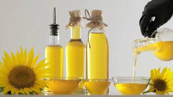 葵花籽油从罐子里倒入玻璃碗里一瓶葵花籽油和黄澄澄的向日葵花近在咫尺金色的油在碗里流淌阳光穿过油流玻璃瓶向日葵油特写慢动作