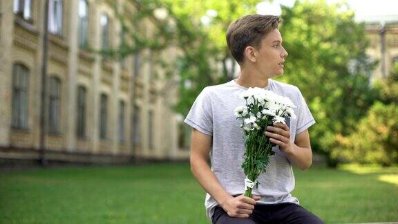 兴奋的少年拿着一束鲜花等待女友满怀期待