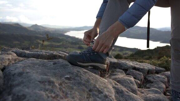 一个不认识的女人在山中徒步旅行系鞋带的特写