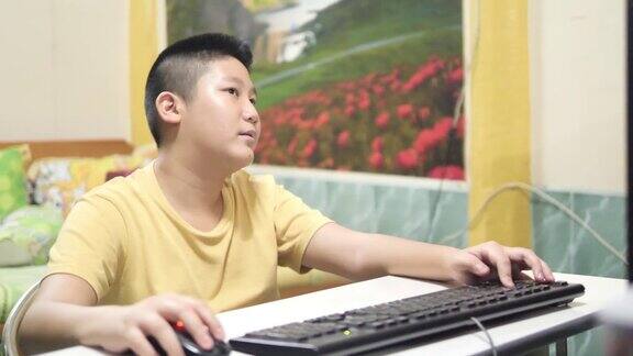 亚洲男孩在家玩电脑网络游戏生活理念