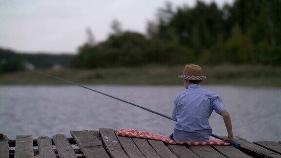 男孩在河中的旧码头上钓鱼