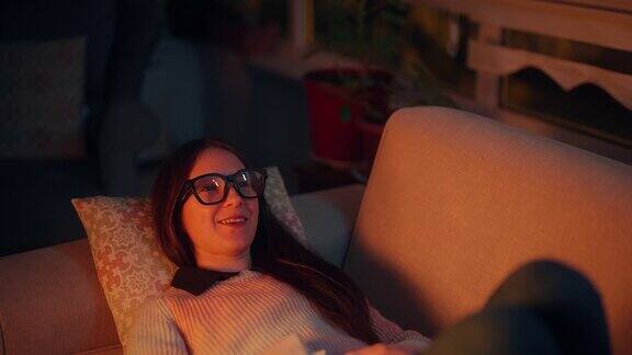 美丽的女人躺在沙发上的肖像和使用智能眼镜元境智能眼镜虚拟现实技术概念