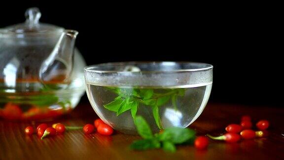 用玻璃茶壶盛着熟透的红枸杞的热茶