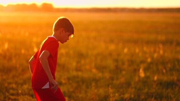 日落时一个小足球运动员在球场上颠球