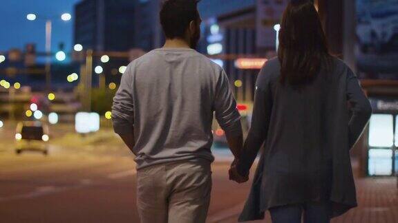 这是一对迷人的幸福夫妇在夜晚小镇的街道上散步