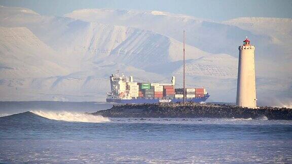 满载的货船在冰岛格罗塔灯塔的雪山中航行
