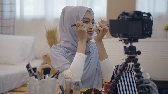 年轻的亚洲穆斯林女性美容影响博主录制视频与化妆品