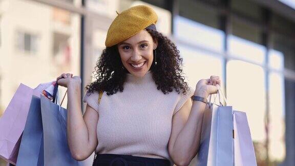 一个年轻的女人提着购物袋走在街上一个年轻女子在城市里疯狂购物后散步