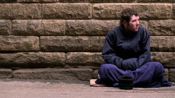 无家可归的人坐在街上乞讨