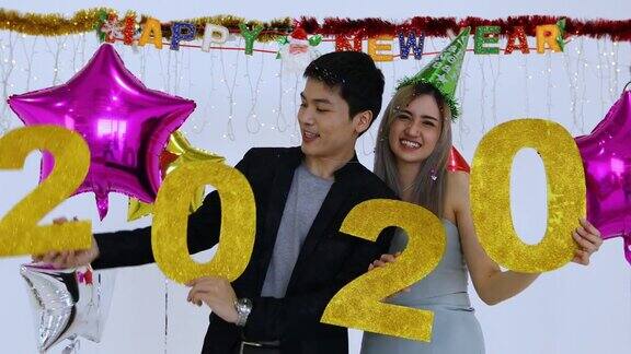 亚洲情侣情侣手持2020数字在酒吧庆祝新年又喊又笑在新年派对上倒数到午夜