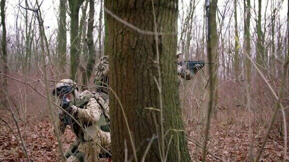 一群年轻的武装士兵在一个地区的武装冲突中穿着制服以突击步枪瞄准森林慢镜头软式