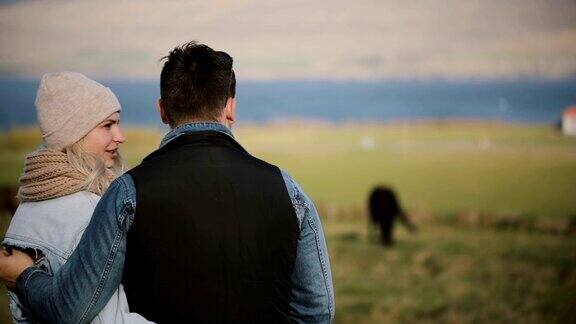 年轻夫妇站在球场上欣赏风景的背影男男女女在看冰岛马