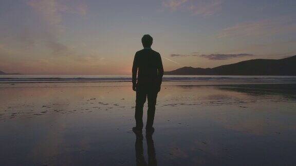 一名男子在日落时站在海滩上的航拍镜头