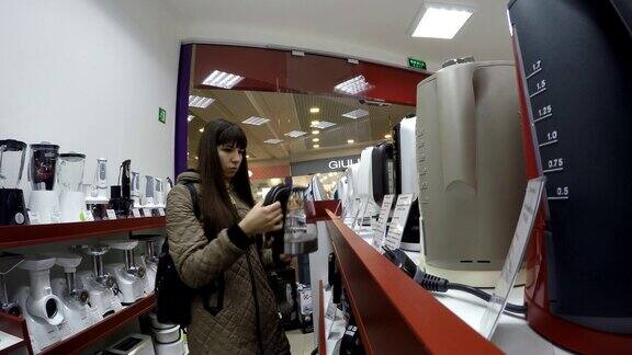 年轻女子在电子商店挑选水壶