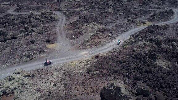 一对夫妇骑着摩托车在通往金塔马尼火山的黑色熔岩路上行驶