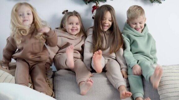 友好的孩子们坐在沙发靠背上在圣诞和新年装饰附近玩耍