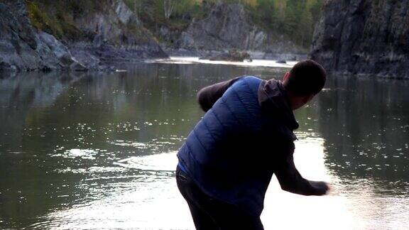一个年轻人往山间的河里扔石头动作很缓慢3840x2160