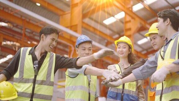 团队合作的象征快乐领导制造业员工团结一致庆祝工作中取得的成功工厂里一群不同技能的工人在一起手拉手