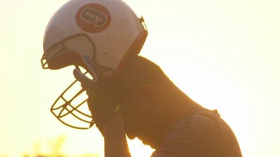 一个足球运动员在日落时戴上他的头盔