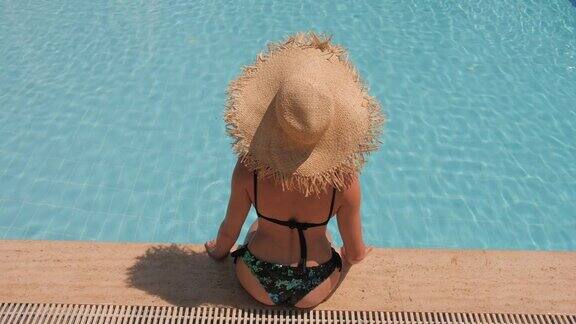 戴着草帽的陌生女子在蓝色的泳池里放松俯视图慢动作