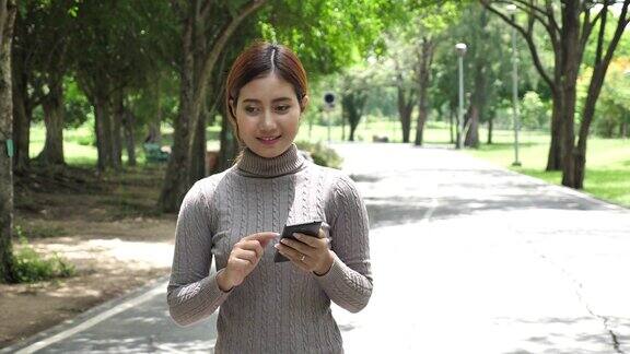 一个女人在公园里散步还在用智能手机