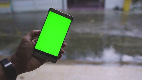 绿屏智能手机和雨背景在城市与雨的声音