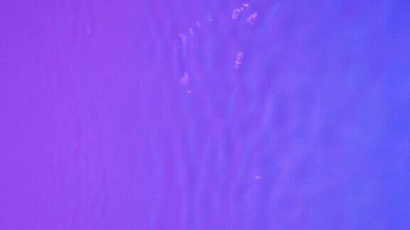 霓虹蓝色粉红色和紫色的水梯度纹理与水滴飞溅和波浪有机水色调的蓝色和粉红色梯度与折射光慢动作视频横幅