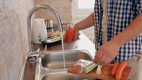 一个面目全非的男人在厨房做饭时洗菜