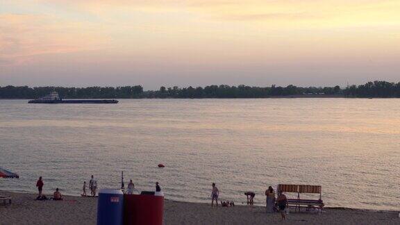 晚上在海滩上放松人们在河岸上休息日落时美丽的海浪潮湿的沙滩