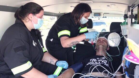 两名女医护人员在救护车上协助一名男病人