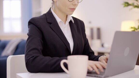 漂亮的女商人戴着眼镜坐在桌子前用笔记本电脑工作