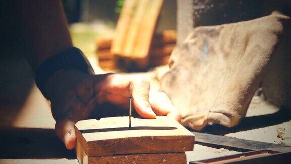 木匠用锤子把钉子敲进未完成的木板
