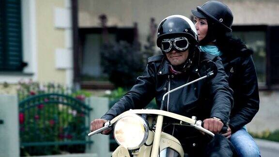 一对夫妇骑着复古摩托车穿过一个小镇