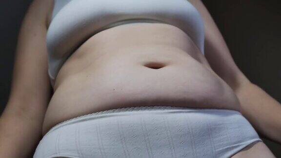 超重的白种女人穿着内衣抖着肚子胖