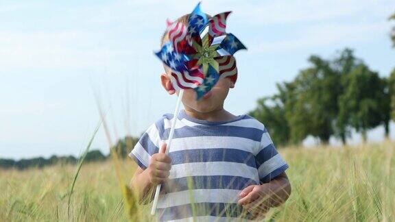 美国一个小男孩在绿色的麦田里玩风车