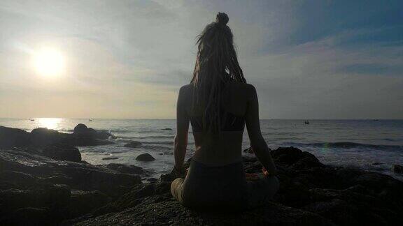日落时练习剪影瑜伽一个年轻女人在海滩上做瑜伽运动