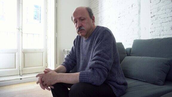 有思想的抑郁和孤独的老人坐在他的沙发上看着窗外的抑郁心理健康概念