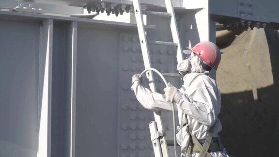 穿防护服的工人用白色油漆油漆建筑结构