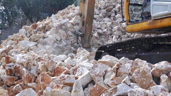 挖掘机用铲斗收集拆除房屋的石块碎片装上卡车