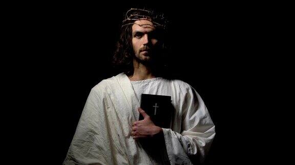戴着荆棘冠冕的人拿着圣经直视耶稣