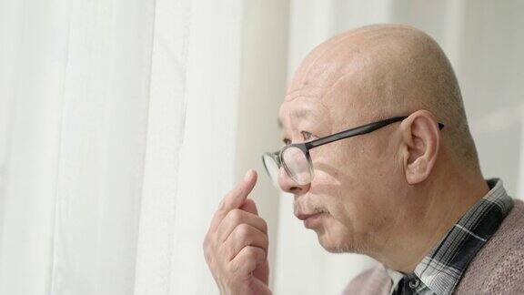 窗前的一位中国老人戴着老花镜凝视着前方