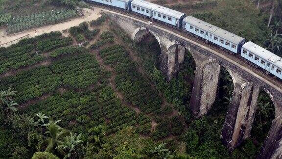 无人机拍摄到斯里兰卡埃拉丛林中著名的蓝色火车经过一座古老的九拱桥