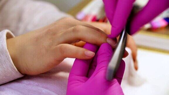 美甲师为客户抛光指甲指甲美容师在美甲沙龙给女人锉指甲女人正在修指甲