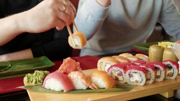 在一家日本餐馆里一对年轻夫妇用筷子从盘子里拿寿司