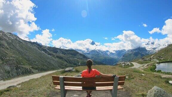 女人坐在长凳上欣赏马特洪峰和瑞士阿尔卑斯山的景色