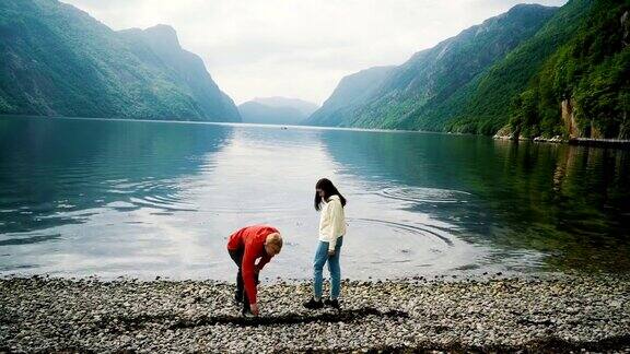 女人和男人在挪威的峡湾里扔石头