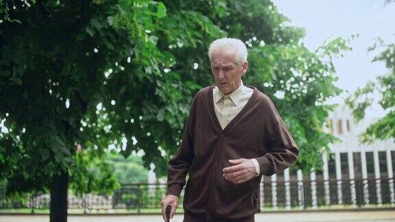 一位老人拄着拐杖在公园里慢慢地走着感到孤独正在康复