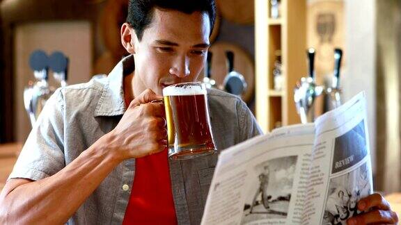 一个在餐厅边喝啤酒边看报纸的男人